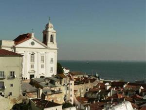 un gran edificio blanco con una torre de reloj en una ciudad en Apartamento vista rio Tejo em Alfama, TTL99, en Lisboa