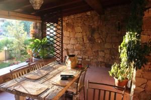 a wooden table with chairs and a stone wall at B&B I Mari in Torpè