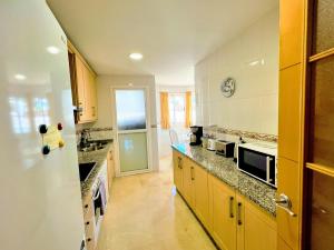 a kitchen with yellow cabinets and granite counter tops at Beautiful apartment with pools, playground and paddle tennis - Family friendly and near Vithas Hospital - Free parking in garage in Benalmádena