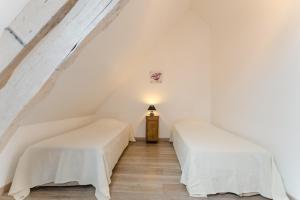 Duas camas num quarto com paredes brancas e pisos em madeira em Le gite de l'orvin em Courgenay