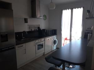 a kitchen with a table and a sink and a dishwasher at La maison de vacances 3 chambres in Sausset-les-Pins +10 photos