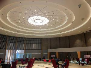 Habitación grande con sillas rojas y techo grande. en Best Cozy Stay in Central Noida , Mall, Free WiFi, Parking, Private Apartment - The Taj Studios, en Noida