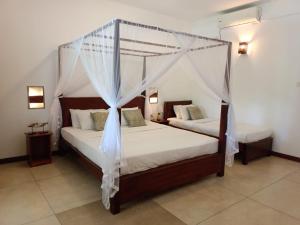 1 dormitorio con 2 camas y 1 cama con dosel en Weligama Ocean Breeze, en Weligama