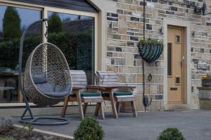 a patio with a swing and two chairs and a table at Bradley Manor in Huddersfield