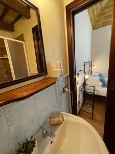 a bathroom with a sink and a mirror and a bed at Ai Dammusi Rooms in San Vito lo Capo