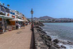 a sidewalk next to the ocean with a street light at Mireya Apartment in Playa Blanca