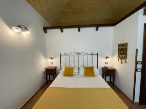a bedroom with a bed with two yellow pillows at Ai Dammusi Rooms in San Vito lo Capo