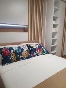 a bed with a floral pillow on top of it at Sarajevo Charm Apartment in Sarajevo