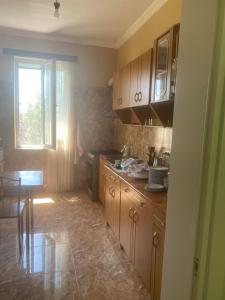 a kitchen with wooden cabinets and a table and a window at Zurkas’ guesthouse in Batumi +2 photos
