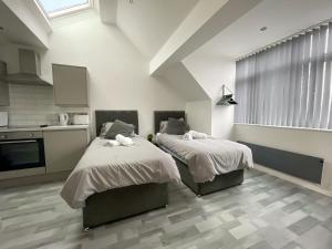 two beds in a room with a kitchen at 10min to City - FREE Parking - Private Studio - Contractor Friendly in Manchester