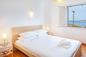 a bedroom with a large white bed with a window at Gaia Seaview Residence Irakleia in Áyios Yeóryios