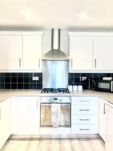 uma cozinha com armários brancos e um forno com placa de fogão em Modern 3 bed home, Chesterfield em Chesterfield