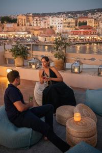 two men sitting on the roof of a building with drinks at Casa Delfino Hotel & Spa in Chania