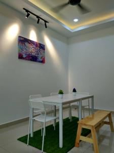 una mesa blanca con sillas y una pintura en la pared en HOMESTAY BATU PAHATKU- HOMESTAY IMAN en Batu Pahat