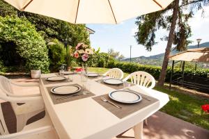 a white table with white chairs and an umbrella at Villa Orchidea by PortofinoHomes in Santa Margherita Ligure