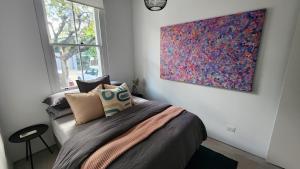 a bedroom with a bed with a painting on the wall at Paddington House in Sydney