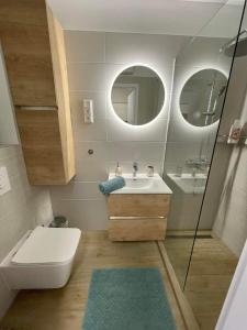 a bathroom with a sink and a toilet and two mirrors at Bella Luna in Balatonfüred