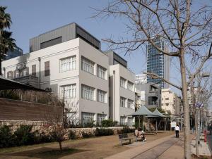 Un grand bâtiment blanc avec des personnes assises devant lui dans l'établissement Romano Neve Tzedek Penthouse, à Tel Aviv