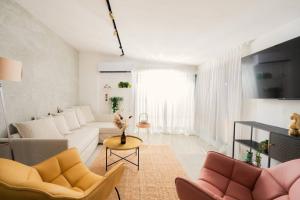 a white living room with a couch and chairs at Romano Neve Tzedek Penthouse in Tel Aviv