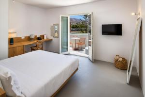 a bedroom with a bed and a desk and a television at Viva Nove Suites in Kamari