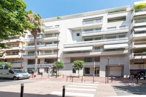 a large white building with a palm tree in front of it at Eden Blue Wilson - Appt climatisé proche plage in Juan-les-Pins