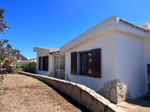 a white house with a stone retaining wall at Villa Elicis in Pinus Village