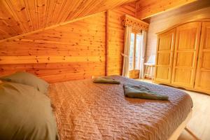 een slaapkamer met een bed in een houten hut bij Le Chant du Ruisseau SPA - Sauna in Le Tholy