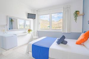 sypialnia z łóżkiem, oknem i telewizorem w obiekcie Hostel Neon Tenerife w mieście Guaza