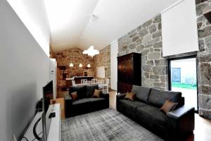 sala de estar con sofá y pared de piedra en Casas do Ermo Ermo Villas, en Fafe