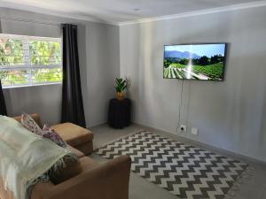 ein Wohnzimmer mit einem Flachbild-TV an der Wand in der Unterkunft Stellenbosch Idasvalley Gem in Stellenbosch