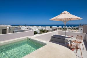 a pool on the roof of a house with an umbrella at Viva Nove Suites in Kamari