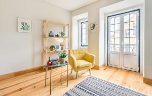 uma sala de estar com uma cadeira amarela e uma mesa em Santos Green Apartment em Lisboa