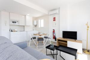 sala de estar con sofá, mesa y cocina en Apartamentos LA PELUSA, en Málaga