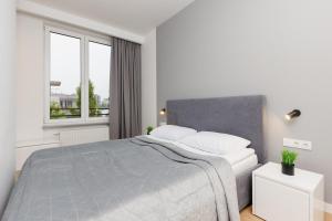 a white bedroom with a bed and a window at Wola Pet-friendly Apartments with AC Sławińska by Renters in Warsaw