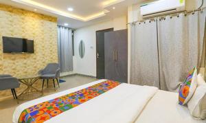 a bedroom with a bed and a tv and a table at FabExpress Namaste Kashi in Varanasi