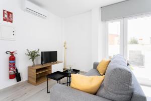 sala de estar con sofá gris y almohadas amarillas en Apartamentos LA PELUSA, en Málaga