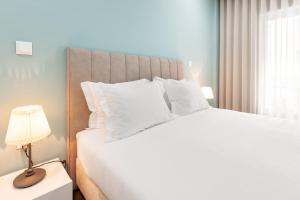 una camera da letto con un grande letto bianco e una lampada di Libertà Lodge Apartment - Minho's Guest a Braga
