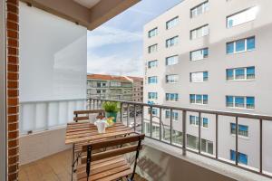 un balcone con tavolo e sedie in legno e un edificio di Libertà Lodge Apartment - Minho's Guest a Braga