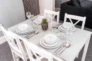 een witte tafel met borden en wijnglazen erop bij Stylish Home with Garden, Free Street Parking in Hull