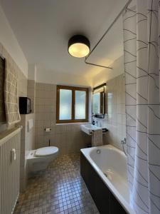 een badkamer met een bad, een toilet en een wastafel bij moderne Ferienwohnung mit Berg- und Isarblick in Mittenwald
