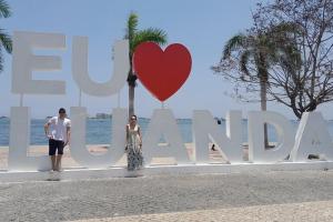 a man and woman standing in front of a sign with a heart at Hospedaria Zac in Luanda