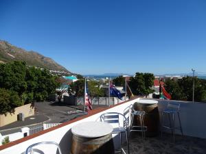 d'un balcon sur le toit avec des tabourets et des tables. dans l'établissement Big Skies Guesthouse, à Gordons Bay