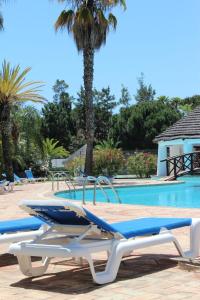 una piscina con due sedie a sdraio accanto a una piscina di Tulio 2 Bedroom Luxury Apartment located in Encosta Do Lago a Quinta do Lago