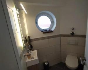 uma casa de banho com um WC e uma janela redonda em Rooftop Apartments - Doppelzimmer in Gemeinschaftsunterkunft (Weinberg R2) em Ulm