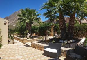 a garden with palm trees and a chair and a fence at Holiday Home Baia Cofano in Custonaci