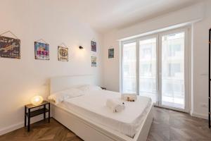ein weißes Schlafzimmer mit einem Bett und einem großen Fenster in der Unterkunft JOIVY Beautiful family flat with a Sea View in Rapallo