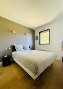 1 dormitorio con 1 cama blanca grande y ventana en Bel appartement cosy dans résidence avec piscine 5 minutes plage, en Messanges