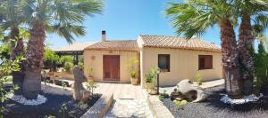 a house with palm trees in front of it at Holiday Home Baia Cofano in Custonaci