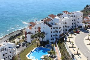 eine Luftansicht auf ein großes weißes Gebäude neben dem Meer in der Unterkunft Apartamento con vistas al mar y parking incluido in Torrox Costa