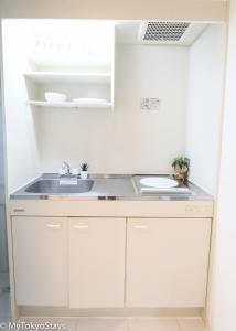 a kitchen with white cabinets and a sink at NEW! Shibuya Square Prime Unit, Heart of Tokyo! in Tokyo